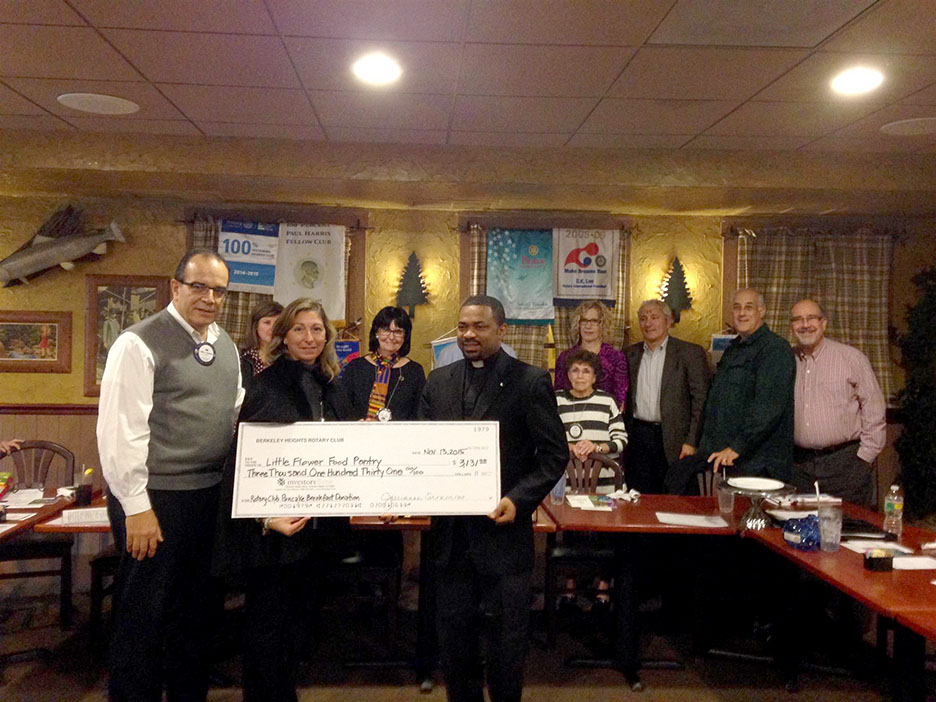 (above, front, l-r) Jim Ramentol, Event Chair front holding check: Catherine Sofaro, Food Pantry; Rev. Nnaemeka ("Andrew") Onyemaobi, Church of the Little Flower (back) Rotary Club members (Center: Linda Sausville, Club President).