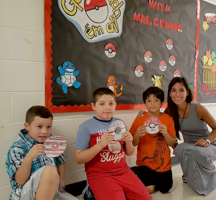 (above) Mrs. Nina Conner and her third grade students Jacob Prystauk, Lucas Origliato, and GianLuca Manzella posing in front of their Pokémon-themed bulletin board.